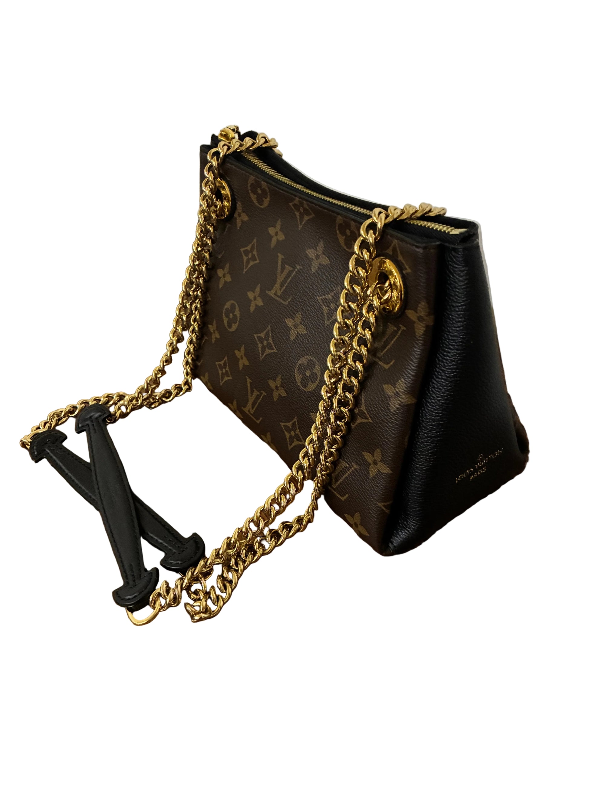 A Louis Vuitton shoulder bag in brown monogram canvas and black leather, featuring a gold-tone chain strap, resting on a wooden table.